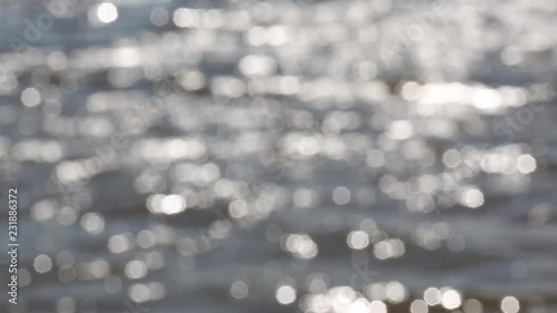 Mesmerizing bright defocused glares from the sun on the wavy surface of the water