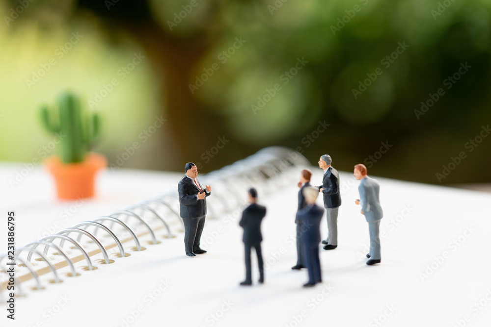 Miniature people meeting on a NoteBook . meeting or Discussion using as background business concept with copy space and white space for your text or design. Miniature people meeting on a NoteBook . meeting or Discussion using as background business concept with copy space and white space for your text or design.