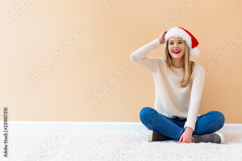 Happy woman with a Santa hat on a white carpet