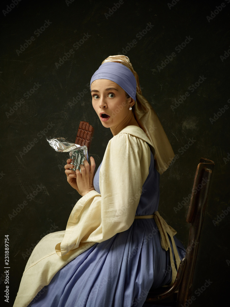 Medieval woman in historical costume wearing corset dress and bonnet.  Beautiful peasant girl wearing thrush costume with sweet chocolate bar over  dark studio Stock Photo | Adobe Stock