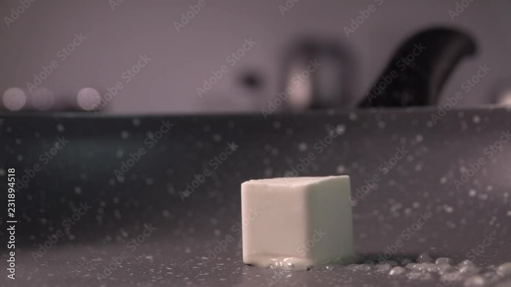 Cube of margarine butter melting in sizzling qranit pan. Slow motion, 240 fps Cube of margarine butter melting in sizzling qranit pan. Slow motion, 240 fps