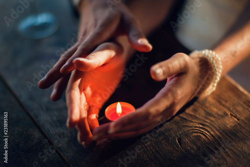 The Touch of love. Lovers in a romantic table holding and touching hands. Valentine's Day. A woman and a man spend candle together on the wood table