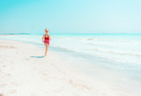 modern girl in red swimwear on seashore jogging