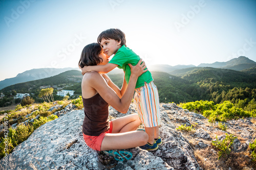 A woman with a child is sitting on top of a mountain.