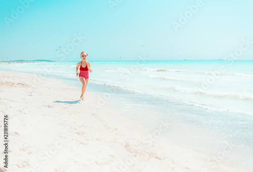 modern girl in red swimwear on seashore jogging