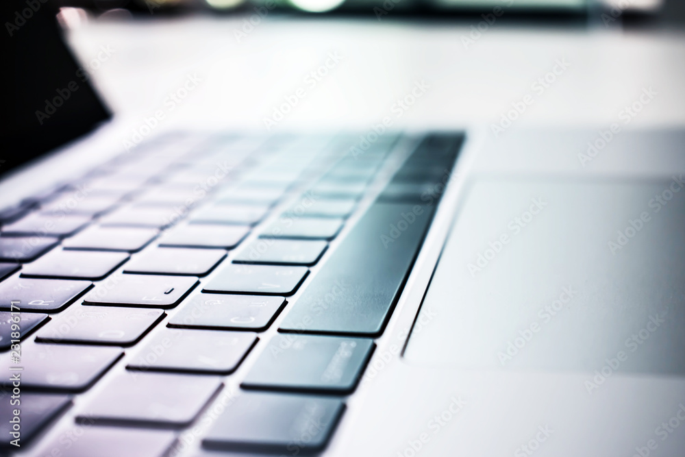 Close up the keyboard on a white table near a large window. Close up the keyboard on a white table near a large window.
