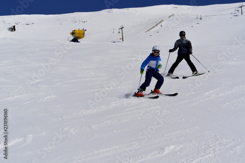 A boy in ski suit, helmet and sunglasses skiing from snowy mountains in Serra Nevada