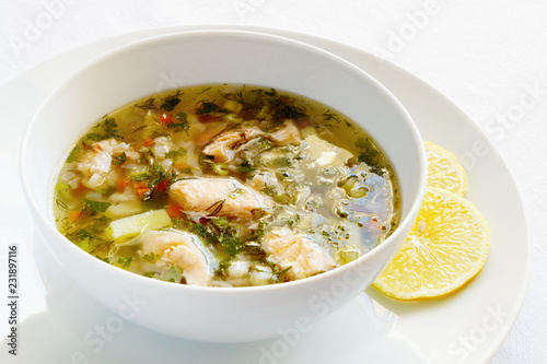 soup with vegetables, barley,herbs, and salmon decorated with lemon slices