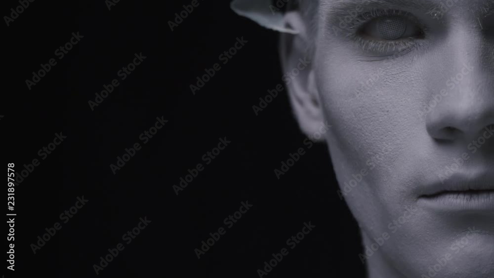 Man with white paint on his face looks with white eyes, close up