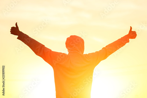 Fototapeta Naklejka Na Ścianę i Meble -  a man in the light of the sunset with his hands up, the concept of success, freedom and joy