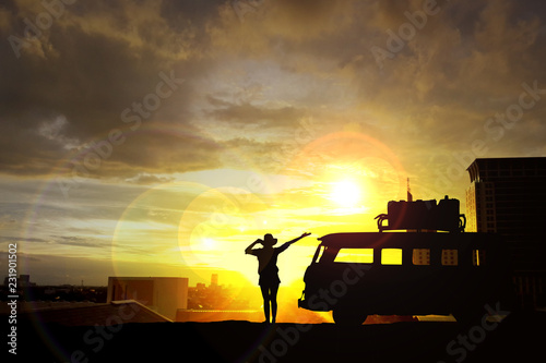 Silhouette of woman raising hands on the building at sunset