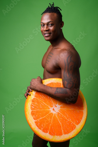 Young handsome African man from Kenya shirtless against green ba photo