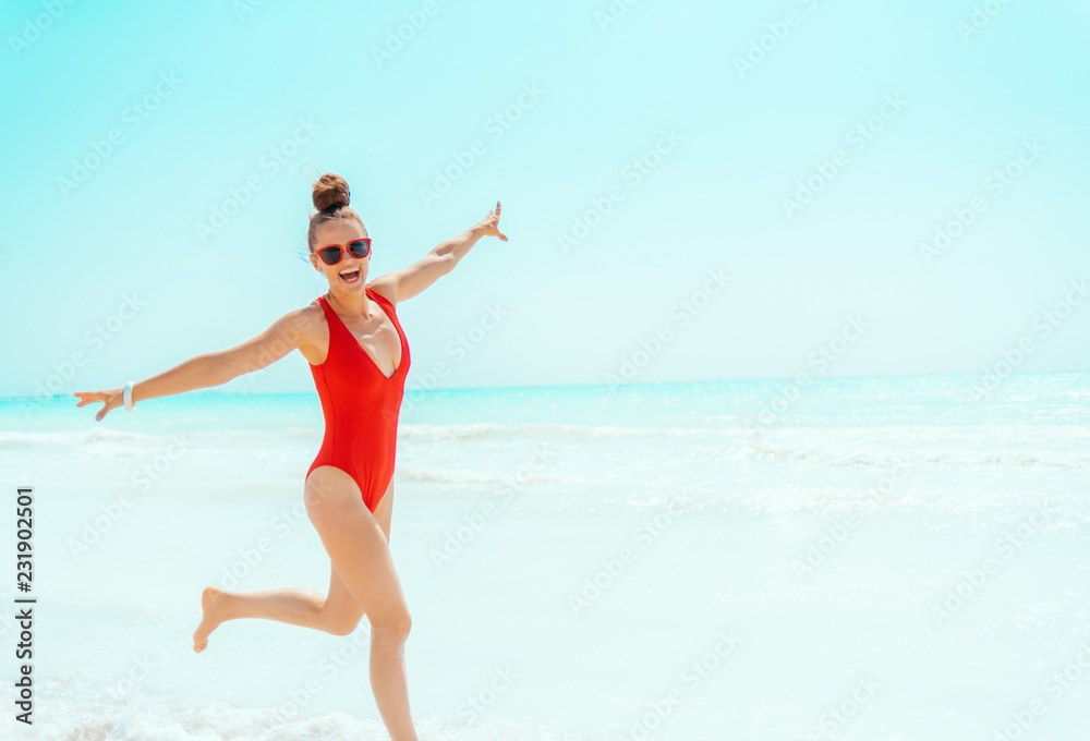 smiling young woman in red beachwear on beach jogging smiling young woman in red beachwear on beach jogging