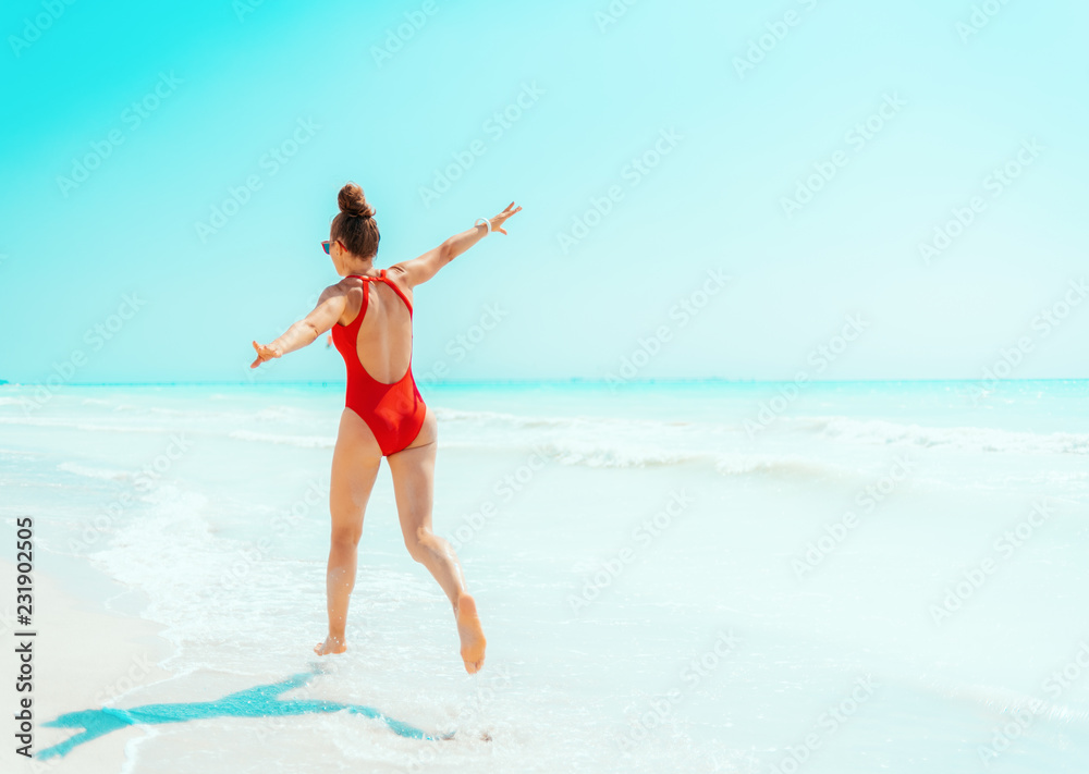 young woman in red swimsuit on seacoast having fun time young woman in red swimsuit on seacoast having fun time