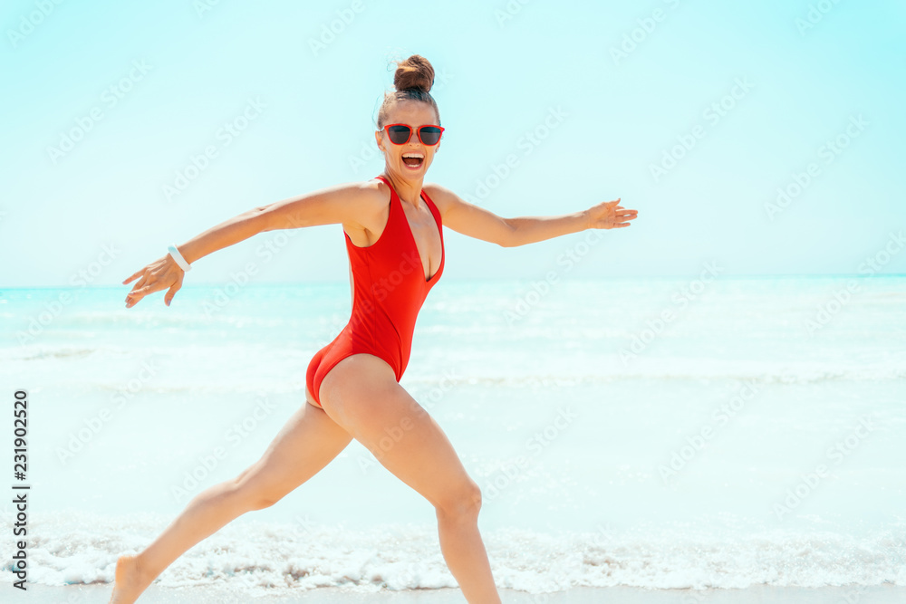 happy modern woman in red swimsuit on seacoast having fun time happy modern woman in red swimsuit on seacoast having fun time