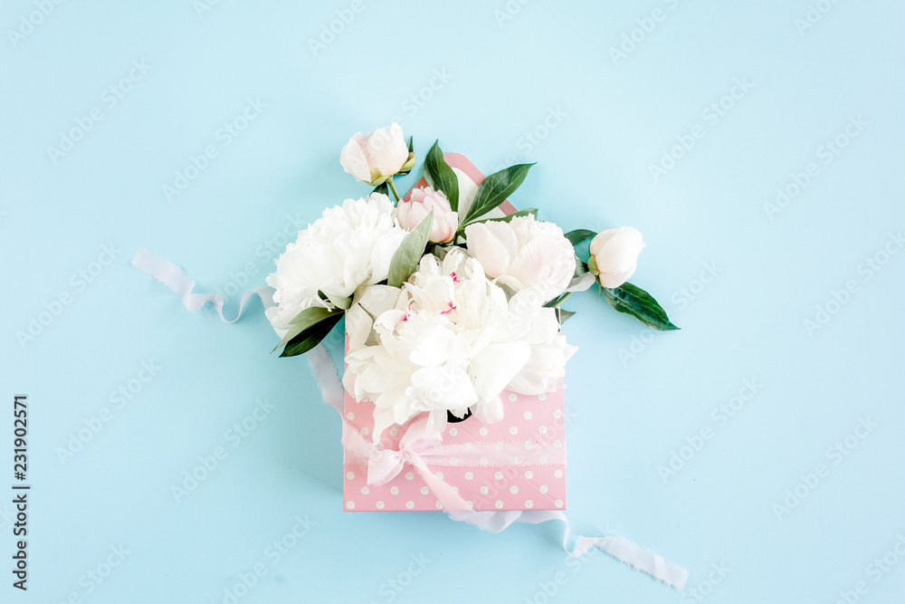 White bouquet of peonies in an envelope for flowers on blue background. Minimal floral concept greeting card. Flat lay, top view. 