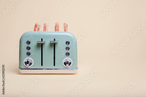 Retro green 4 slice toaster on a vintage tan background with four slices of toast popping out
