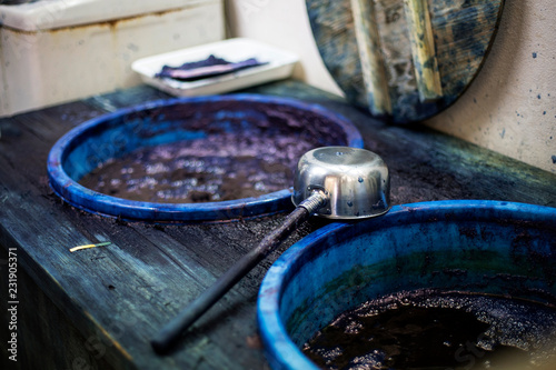 High angle close up of ladle and buckets with blue dye in a textile plant dye workshop.