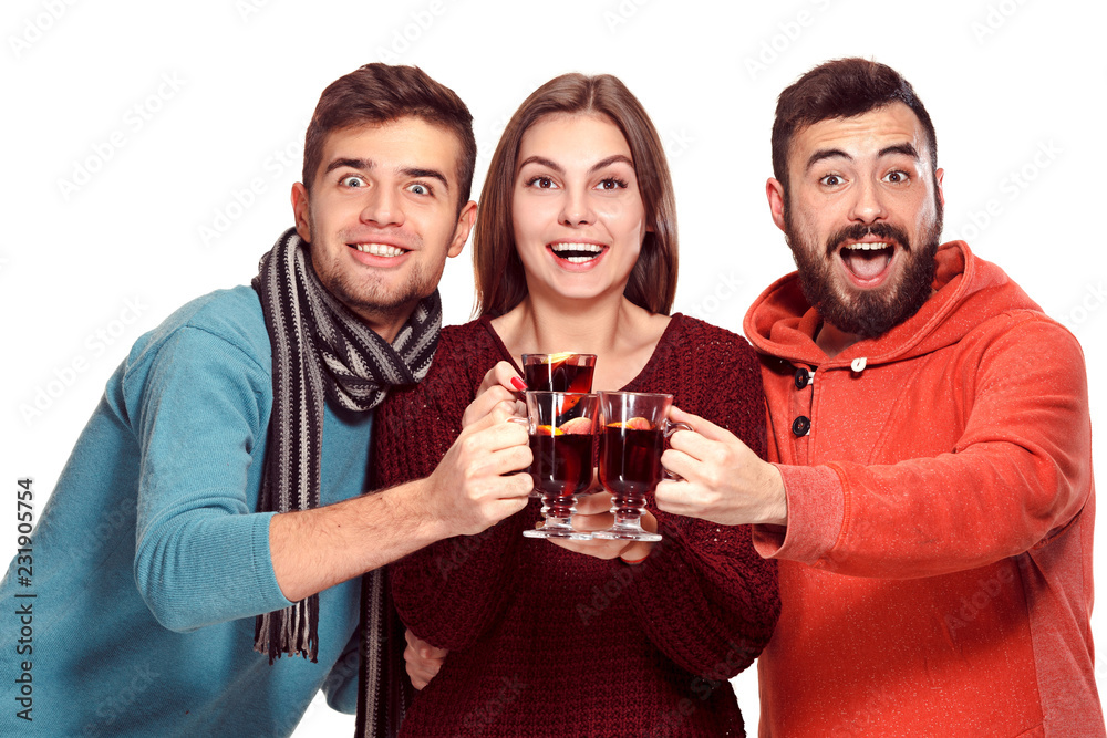 Smiling european men and women during party photoshoot. The guys posing as friends at studio fest with wineglasses with hot mulled wine on foreground. Smiling european men and women during party photoshoot. The guys posing as friends at studio fest with wineglasses with hot mulled wine on foreground.