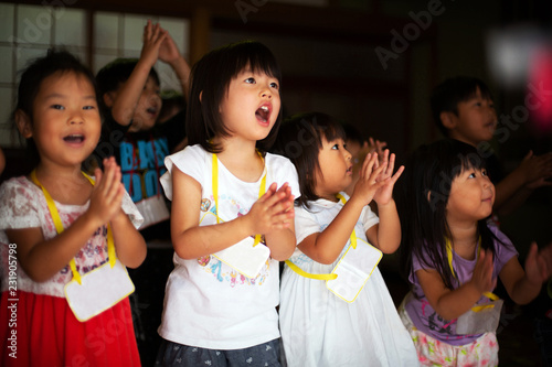 Group of children, girls and boys singing and clapping together in a temple. 