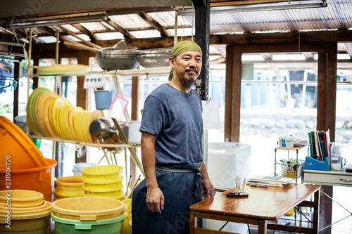 Japanese man wearing bandana standing in a textile plant dye workshop, smiling at camera. photo