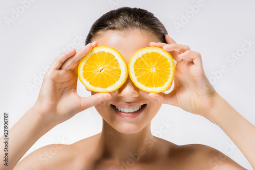 young smiling woman with orange slices on eyes photo