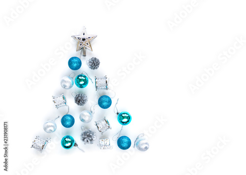 Christmas tree decorative ornaments of silver star, blue balls, pine cone, tinsels and drums over white background arranged in pine tree shape with copy space for winter Merry X'mas text insertion