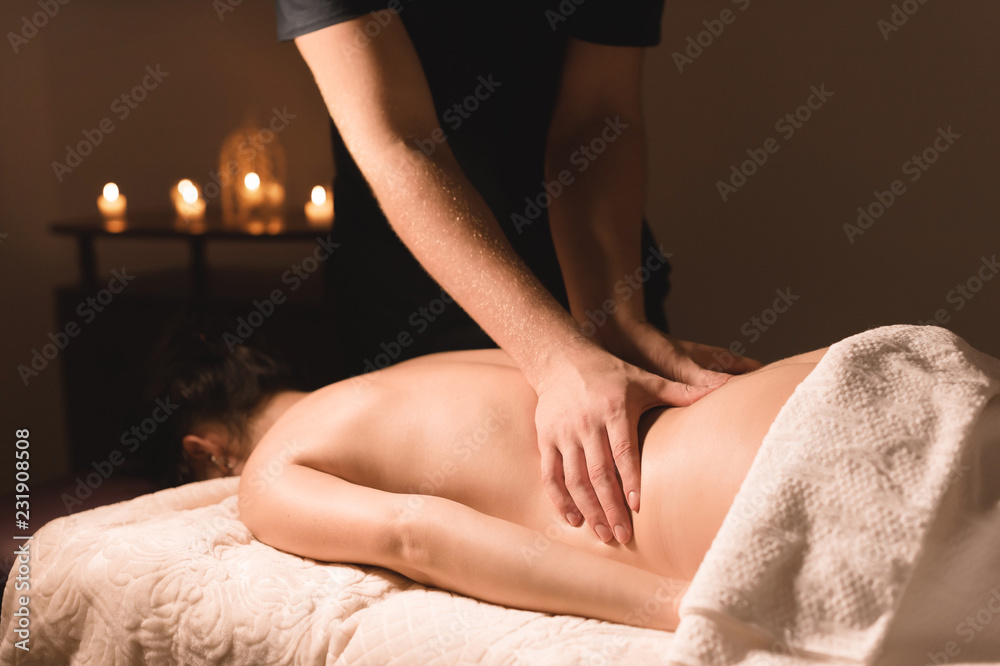 Fototapeta premium Close-up of male hands. Masseur does massage for the waist of a young girl. Rehabilitation, beauty therapy medicine. healthy concept