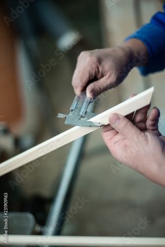 Carpenter at work in workshop, a man makes measurements