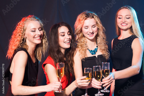 Party, holidays, celebration and nightlife concept - smiling female friends with glasses of champagne in club