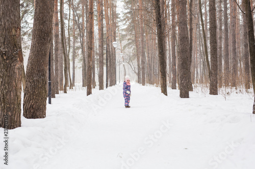 Child running in snowy forest. Toddler kid playing outdoors. Kid play in snowy park.