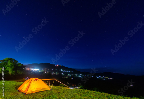 Orange tent glows under night sky.