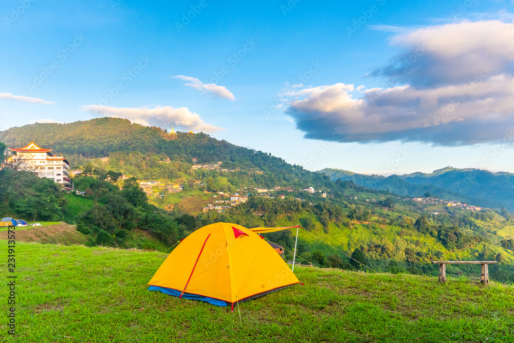 Camping orange tent on the mountain during sunrise in Chiang Rai, Thailand.