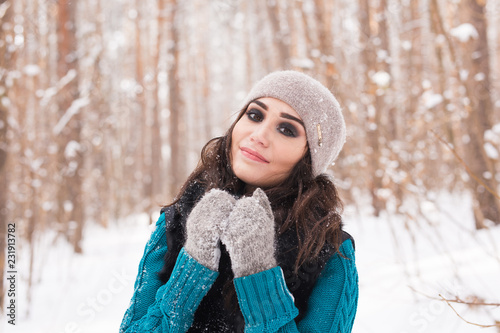 Happy young woman walking in winter time. Portrait of pretty girl in snowy nature