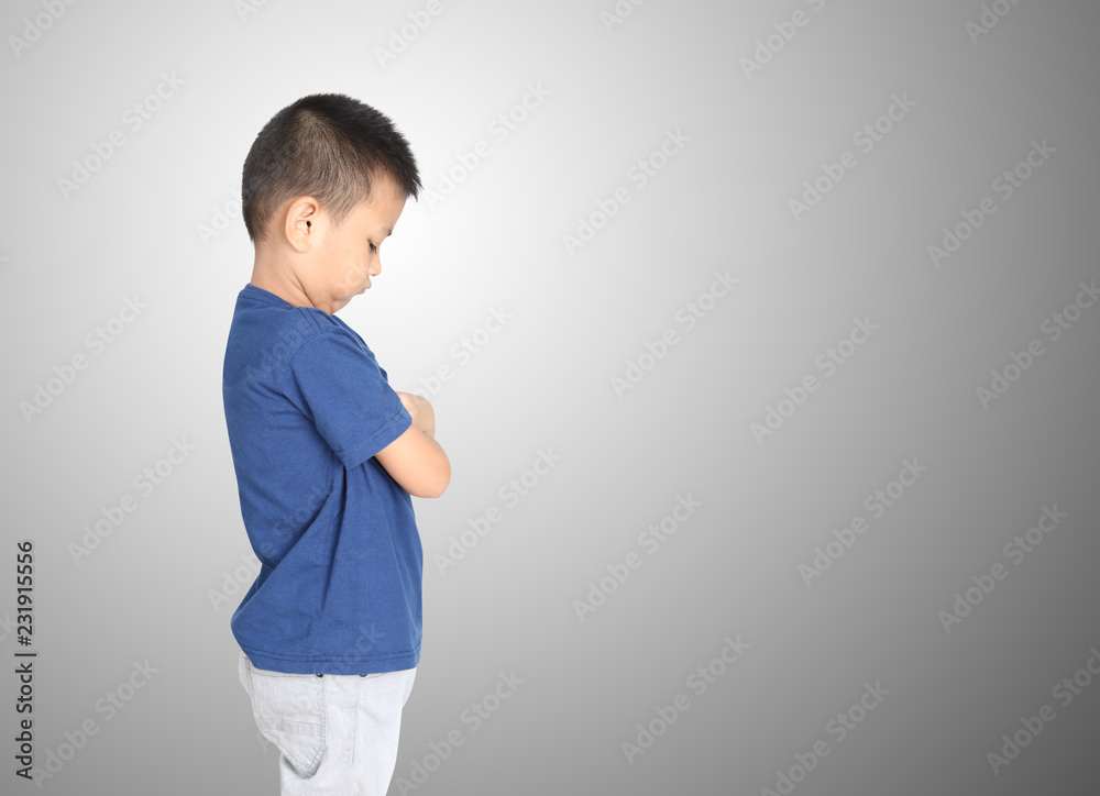Guilty and abused little asian boy standing with arms crossed