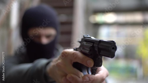 Bandit with black gun , robber on the street, urban abandoned background
