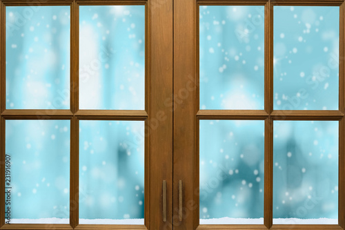 Wooden window frame with outside view of snow and nice freezing blue tone bokeh in background.