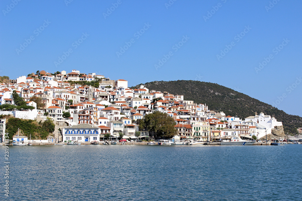 Skopelos town island greece mediterranean harbor port houses church hill sky cityscape coastline panorama
