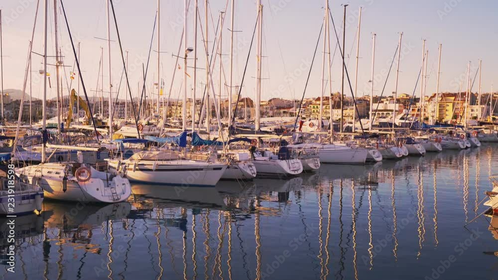 Boats docked in sea port at sunset. Mediterranean fishermen village of Cambrils in Spain. Tranquility, relaxation and fashionable vacation.