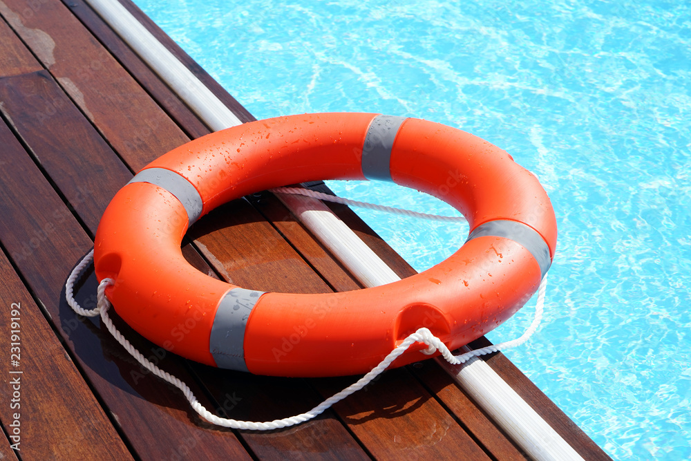 Φωτογραφία The red life ring lies on the wooden floor of the swimming pool