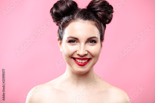Beauty portrait of young brunette woman on a bright pink background. Model with make-up and hairstyle, closeup, fashion glamour photo