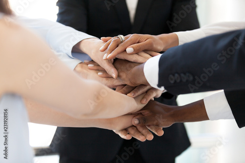 Close up of diverse employees stack hands in pile show mutual support, multiethnic workers promise loyalty and help involved in team building activity, team united at motivational business training photo