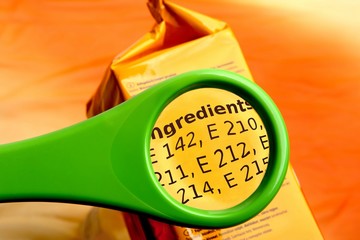 Concept of reading ingredients list on food package with magnifying glass. Magnifying glass on food additives label. 