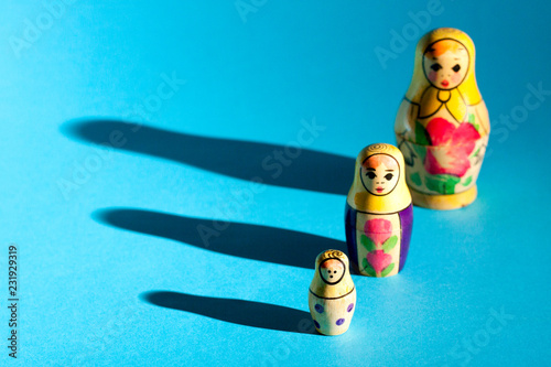 Row of nesting dolls with hard shadows on background