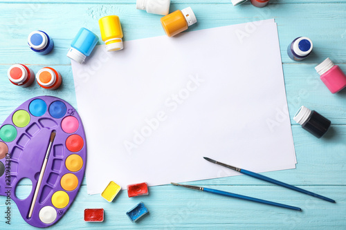 Flat lay composition with empty paper and painting supplies for child on table. Space for text