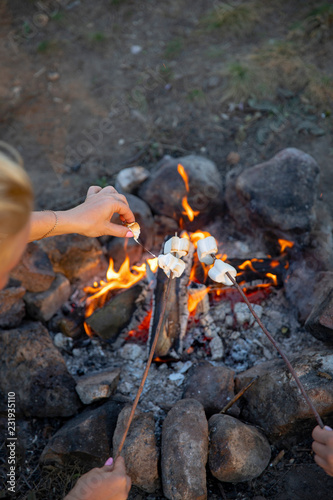 Cooking marshmallow on sticks on a fire.