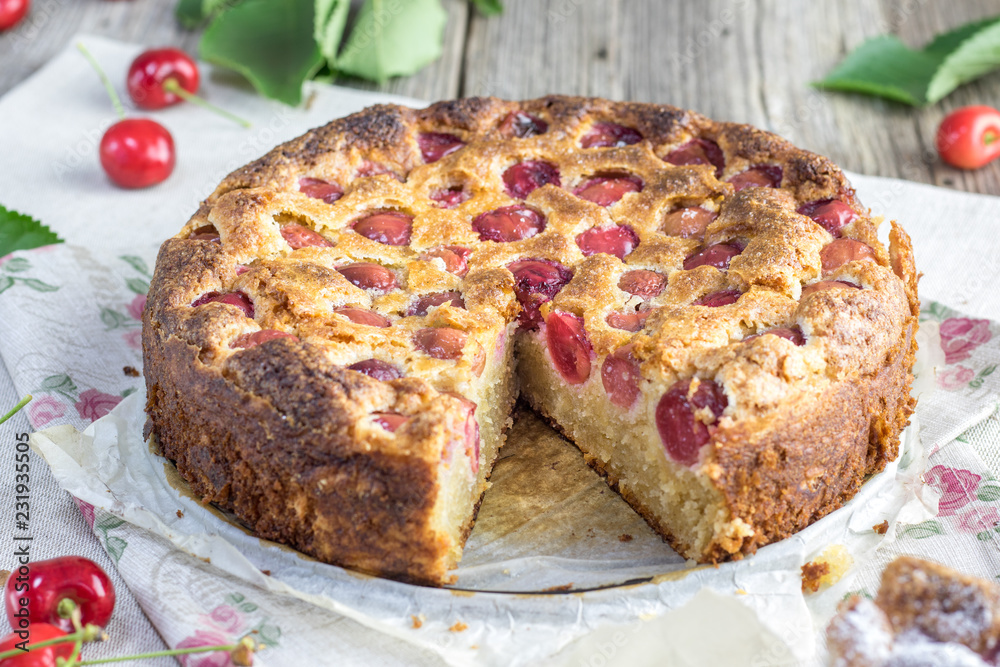 Cuted czech rounded black cherries bubble cake or souffle on wooden table.