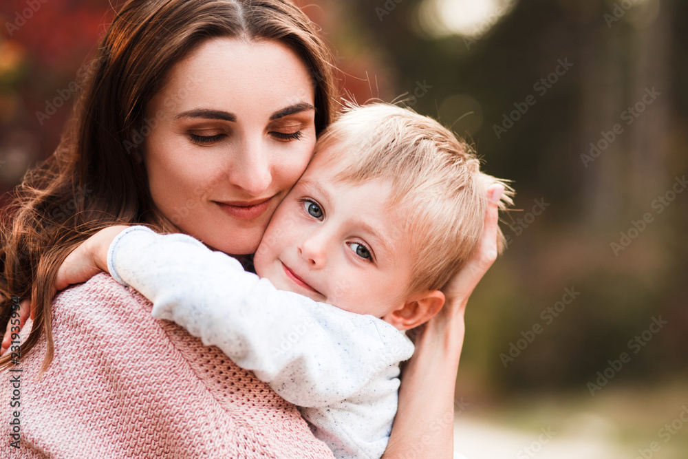 Mom and son hug and laugh in the autumn park. Space for text. Mom and son hug and laugh in the autumn park. Space for text.