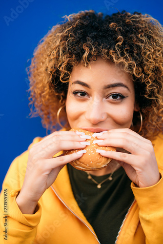 Young woman eating a burger on the street