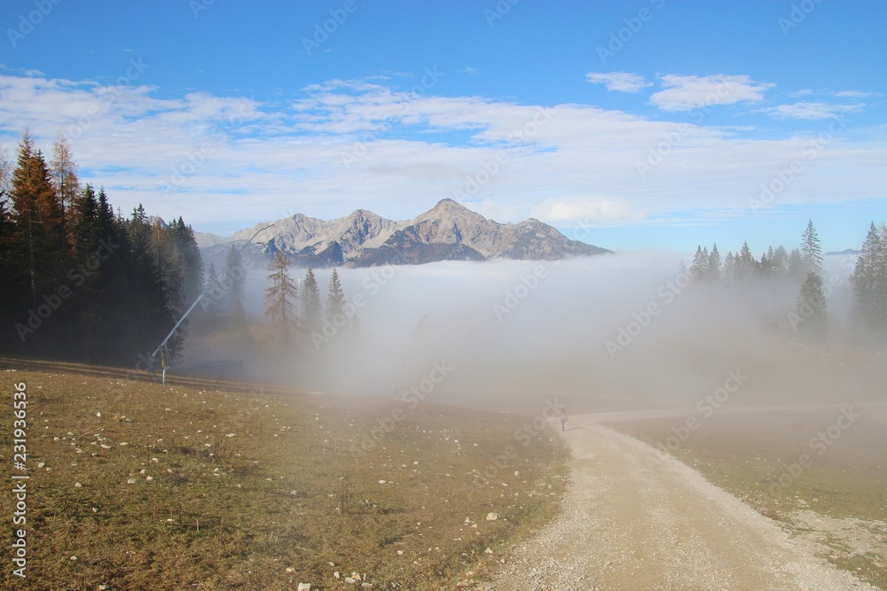 Trail in the mountains in autumn, in the Limestone alps national park, above Hinterstoder. Height approx. 1300 m.  A fog layer above the valley. Upper Austria, Europe.